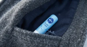A compact tube of the best hydrating lip balm resting inside a winter coat pocket.